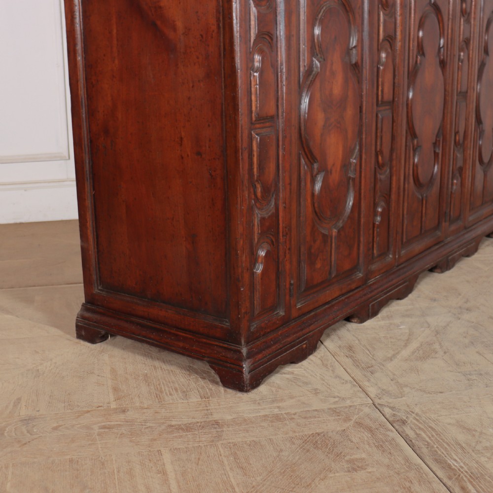 An antique dark walnut Italian sideboard featuring three upper frieze drawers and three carved panelled doors. View XIII