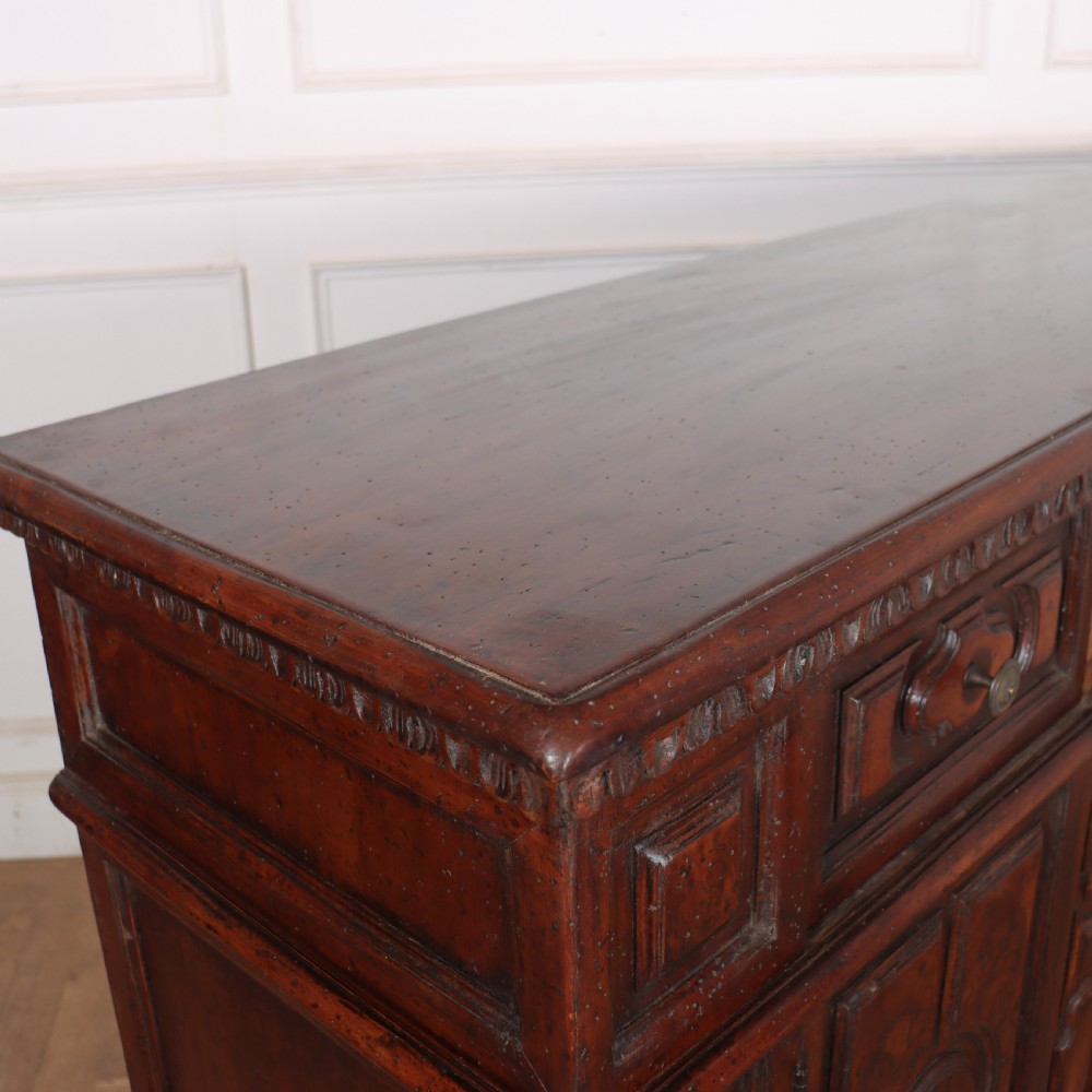 An antique dark walnut Italian sideboard featuring three upper frieze drawers and three carved panelled doors. View XV