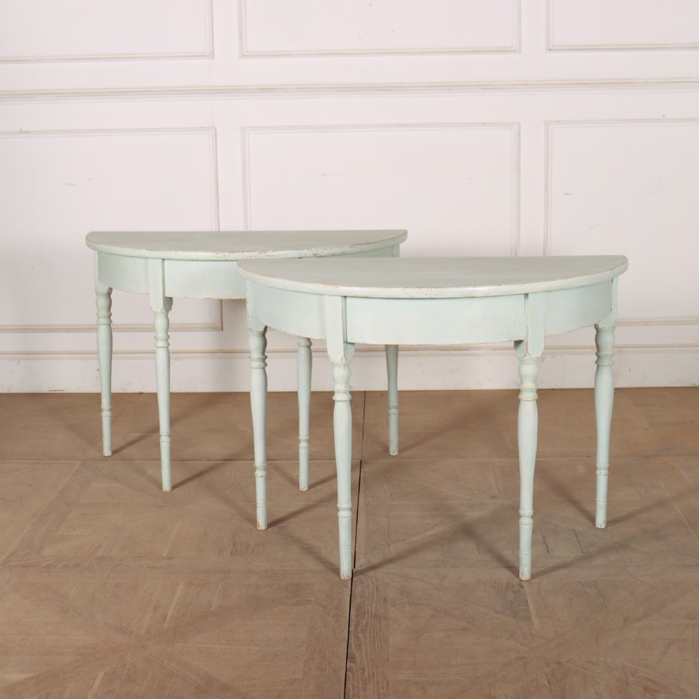 A pair of semi-circular Swedish console tables featuring pale green painted finishes, turned legs, and flat back edges.