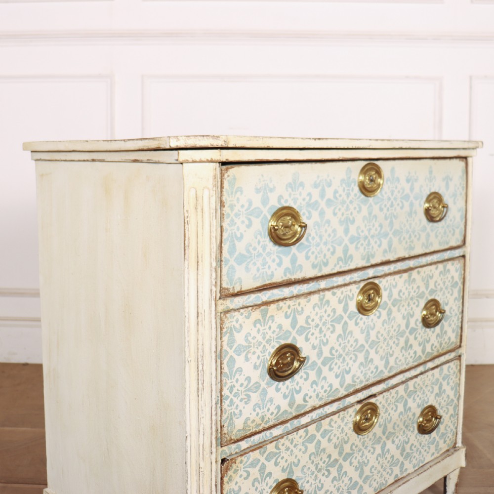A Swedish painted oak commode featuring three drawers with light blue stencilled motifs, brass ring handles, and fluted corner pilasters. View VIII