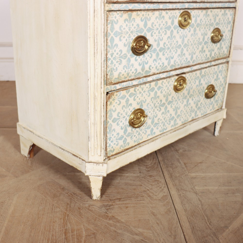 A Swedish painted oak commode featuring three drawers with light blue stencilled motifs, brass ring handles, and fluted corner pilasters. View IX