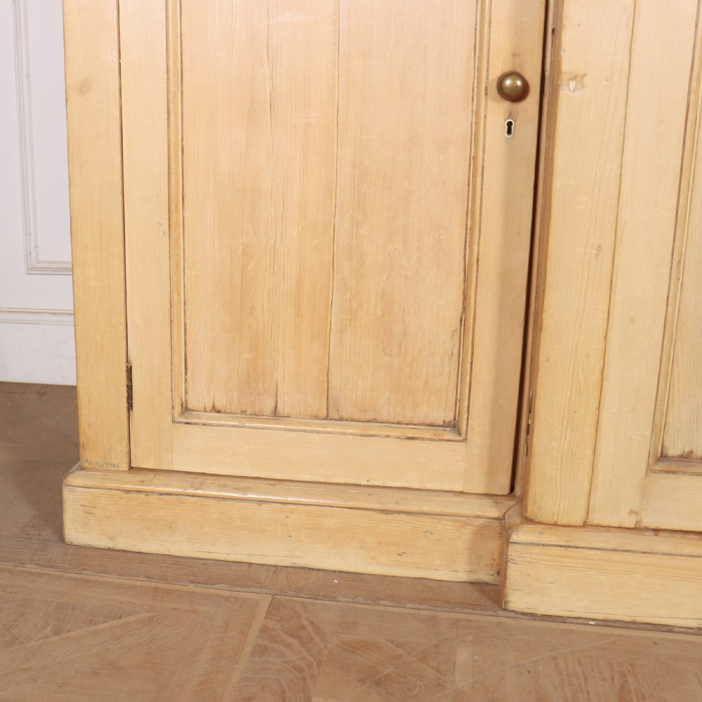 A wide English pine breakfront cupboard featuring four recessed panel doors, brass knobs, and a projecting central section. View II