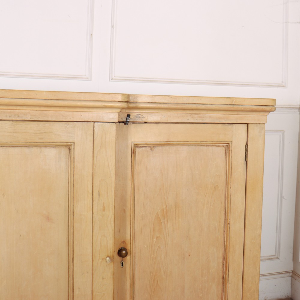 A wide English pine breakfront cupboard featuring four recessed panel doors, brass knobs, and a projecting central section. View III