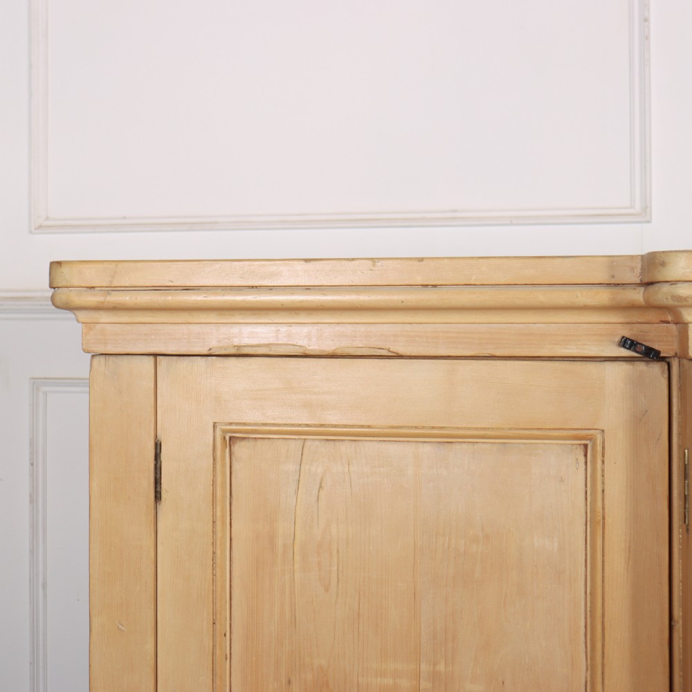 A wide English pine breakfront cupboard featuring four recessed panel doors, brass knobs, and a projecting central section. View VI