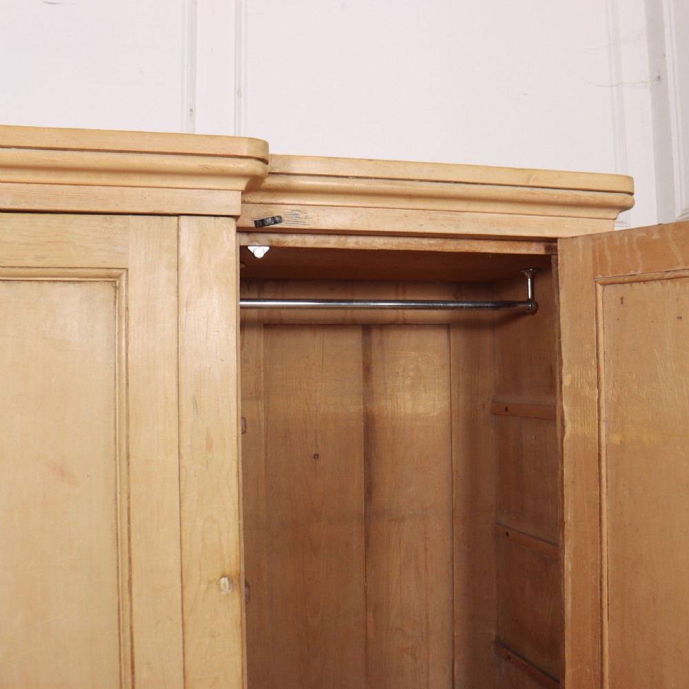 A wide English pine breakfront cupboard featuring four recessed panel doors, brass knobs, and a projecting central section. View IX