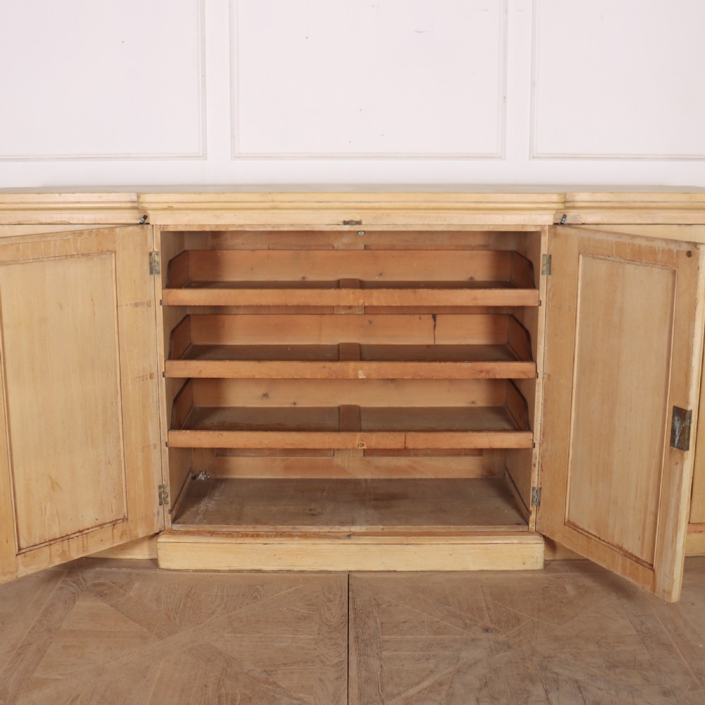 A wide English pine breakfront cupboard featuring four recessed panel doors, brass knobs, and a projecting central section. View X