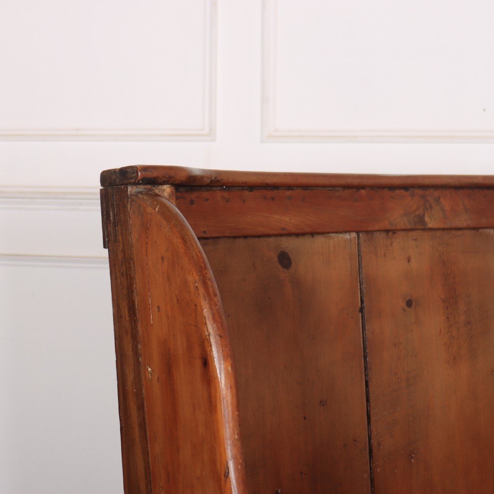 A high-backed antique pine wooden settle featuring tall vertical plank panels, curved side wings, and a floral upholstered seat cushion. View III