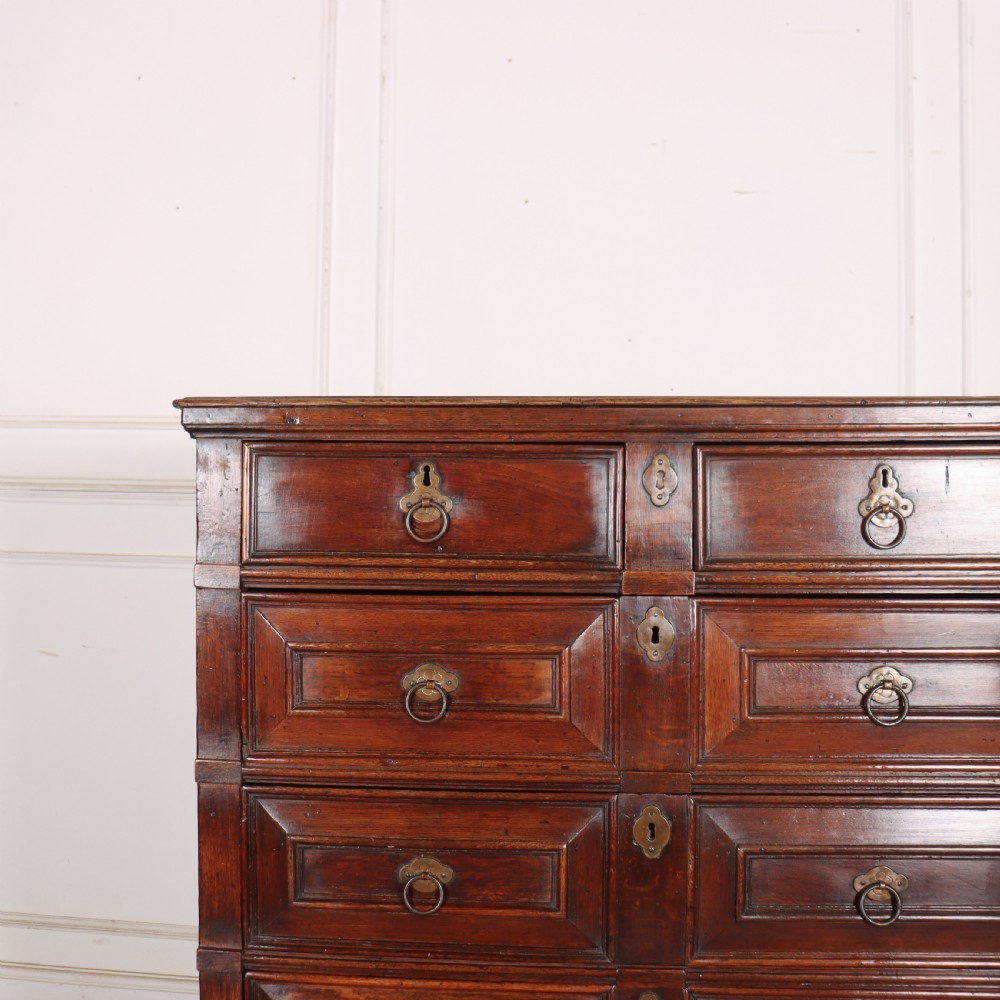 A warm brown wooden antique chest on stand with geometric moulded drawer fronts, brass drop handles, and slender cabriole legs. View II