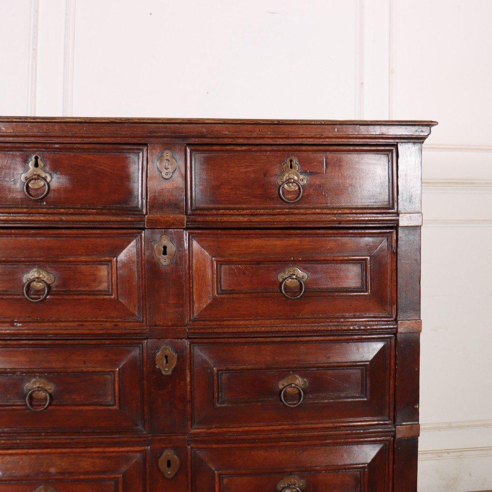 A warm brown wooden antique chest on stand with geometric moulded drawer fronts, brass drop handles, and slender cabriole legs. View III