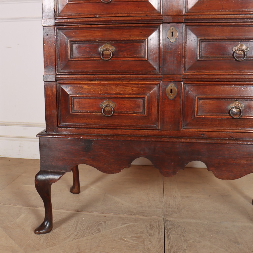 A warm brown wooden antique chest on stand with geometric moulded drawer fronts, brass drop handles, and slender cabriole legs. View VI