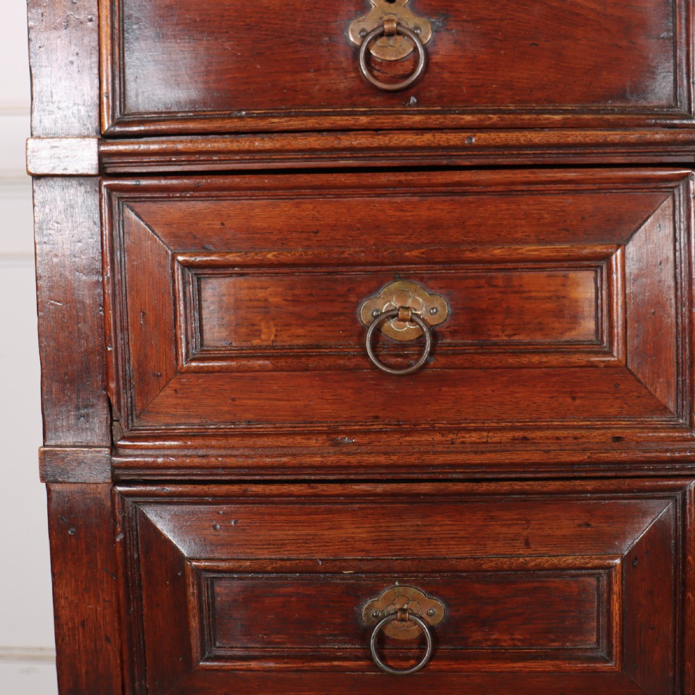 A warm brown wooden antique chest on stand with geometric moulded drawer fronts, brass drop handles, and slender cabriole legs. View VIII