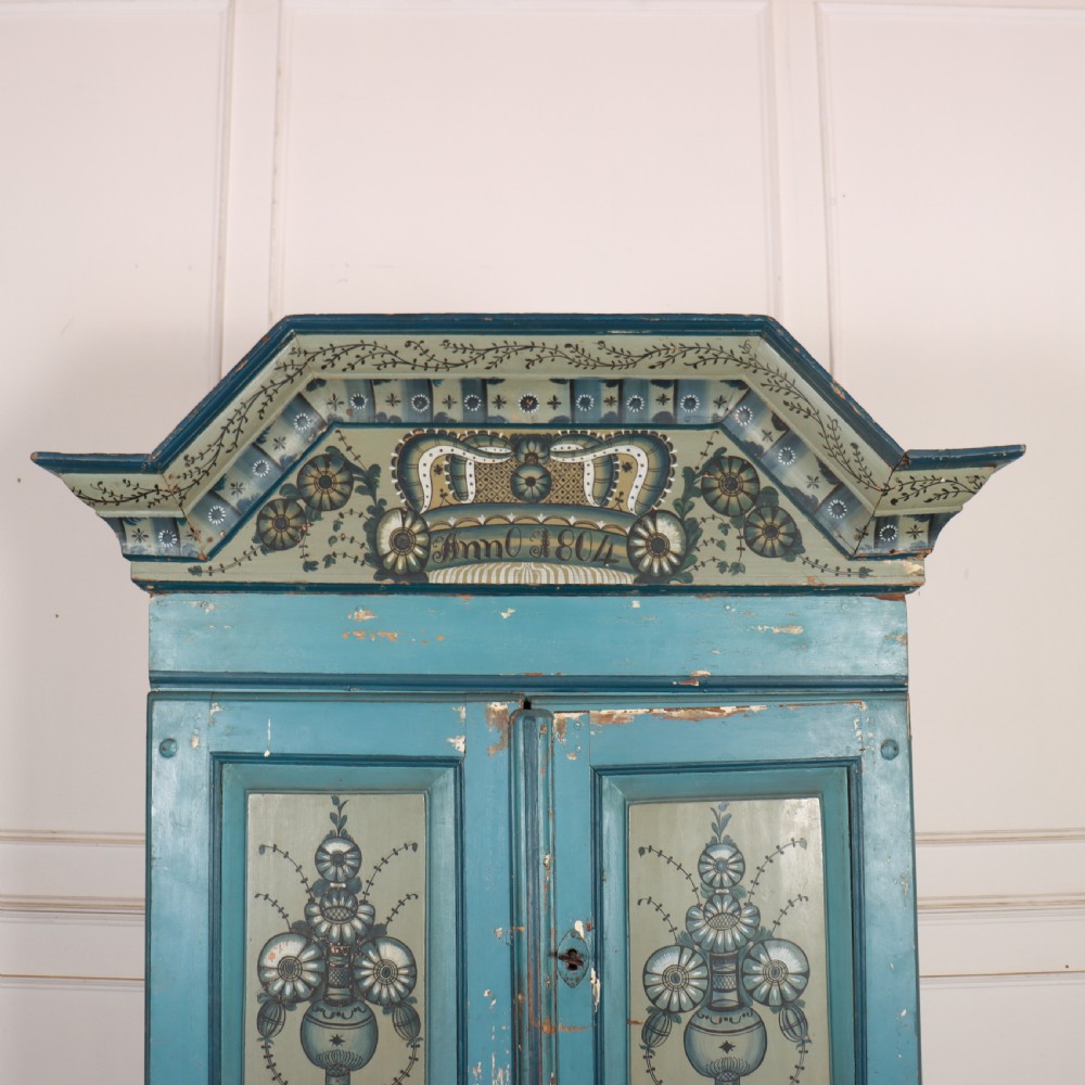 A two-tier antique Gustavian Swedish cabinet painted in blue with hand-painted urn motif panels and a dated pediment top. View II