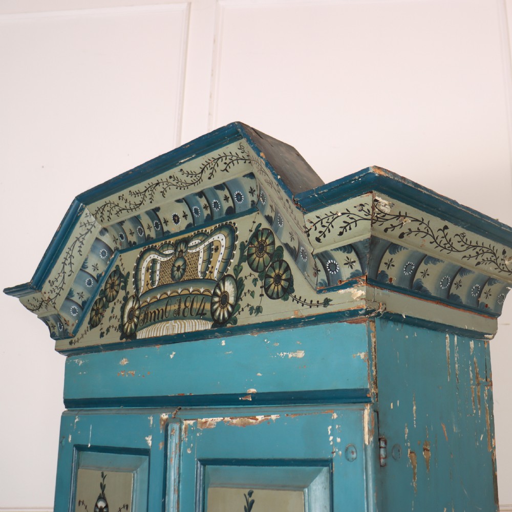 A two-tier antique Gustavian Swedish cabinet painted in blue with hand-painted urn motif panels and a dated pediment top. View VII