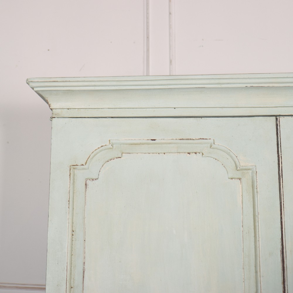 A two-piece pale blue painted timber hanging cupboard featuring panelled doors over a base with drawers and brass handles. View II