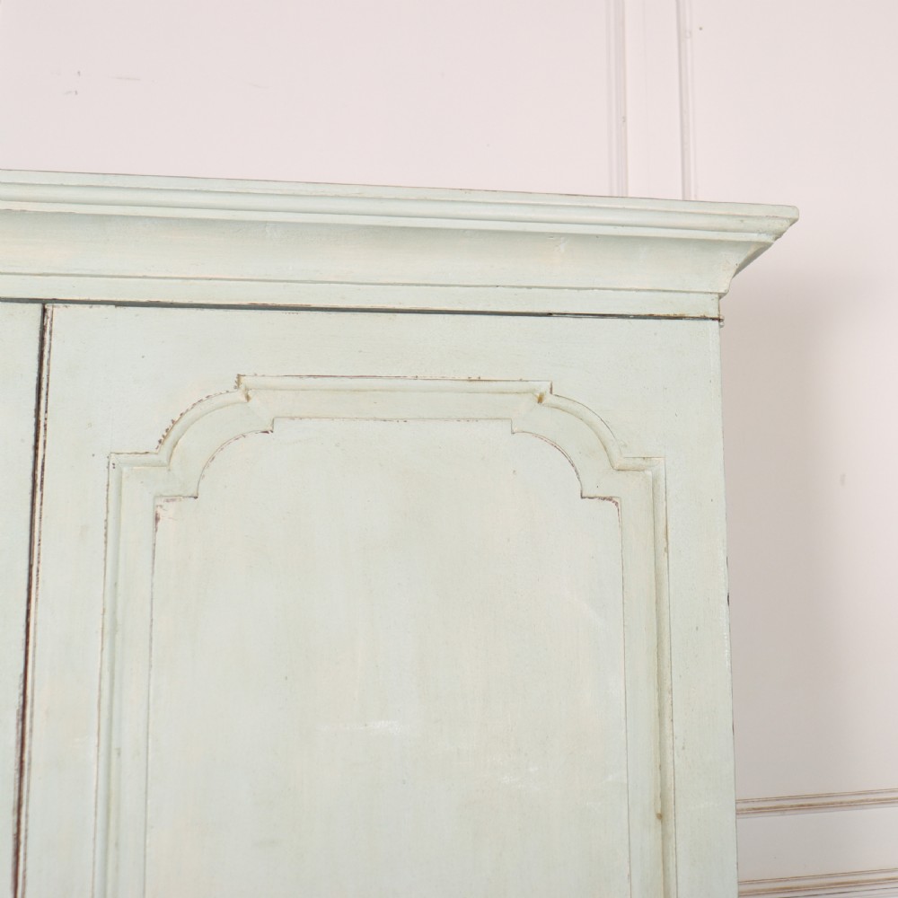 A two-piece pale blue painted timber hanging cupboard featuring panelled doors over a base with drawers and brass handles. View III