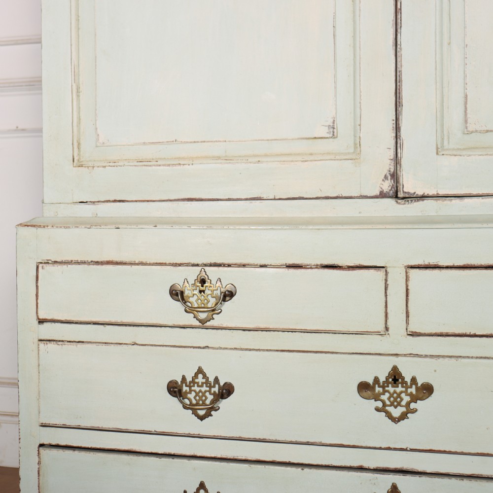 A two-piece pale blue painted timber hanging cupboard featuring panelled doors over a base with drawers and brass handles. View V
