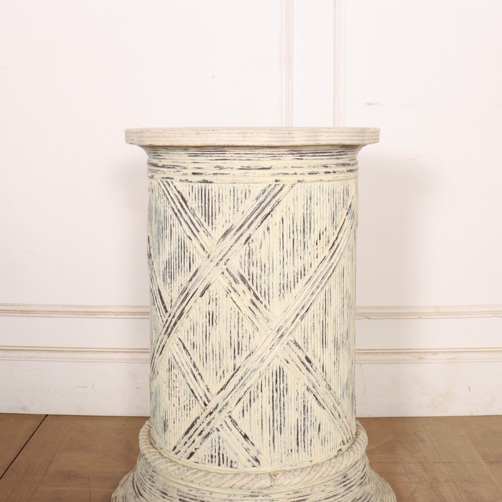 A cylindrical off-white painted wooden sculpture stand featuring carved cross-hatching patterns, a rope-twist lower border, and a distressed finish. View III