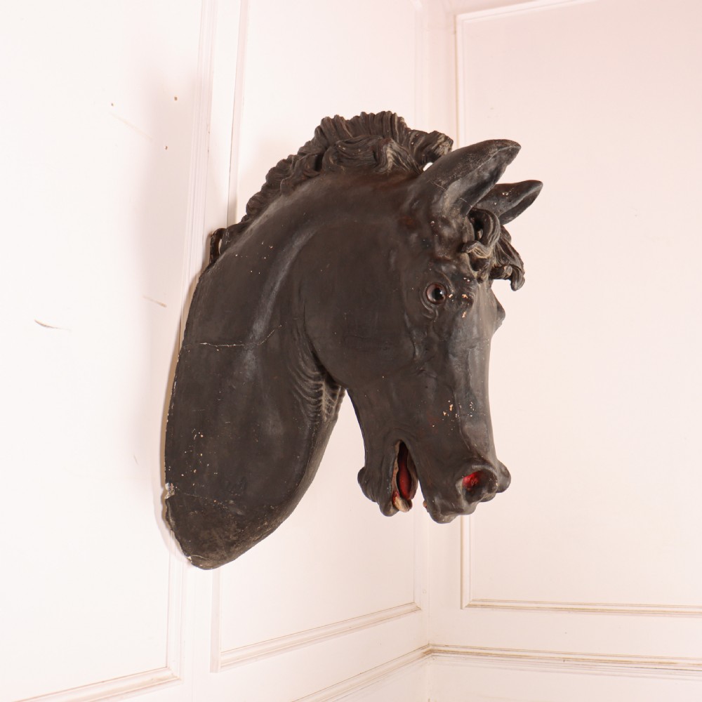 A 19th-century dark painted plaster wall-mounted bust of a horse head in profile showing fine carved details.