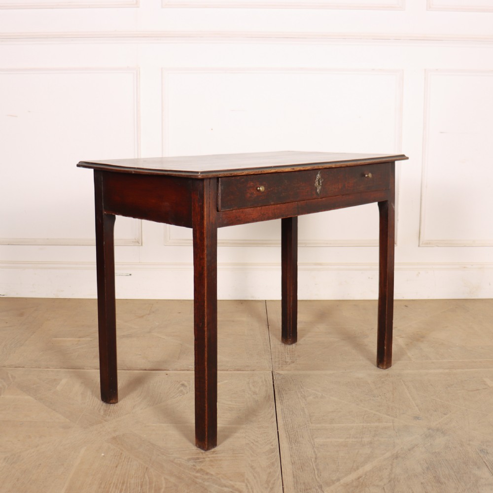 An antique dark oak lamp table featuring a single frieze drawer with brass knobs and a decorative keyhole escutcheon.