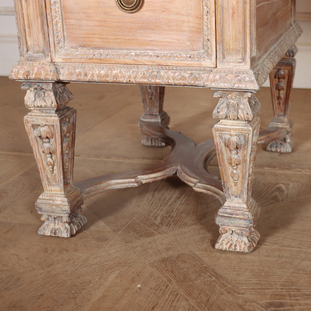 A pale bleached oak kneehole writing desk with intricate carved legs, five drawers with brass drop handles, and double X-frame stretchers. View V