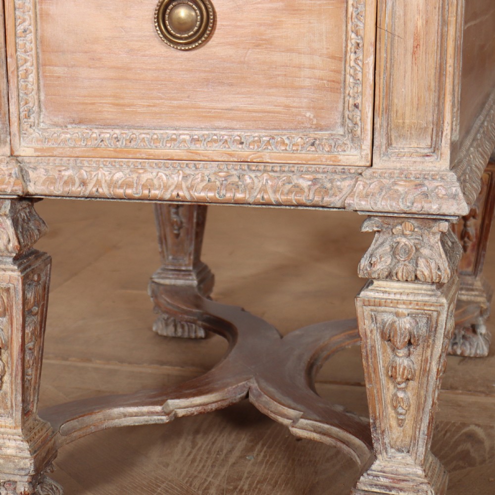 A pale bleached oak kneehole writing desk with intricate carved legs, five drawers with brass drop handles, and double X-frame stretchers. View VI