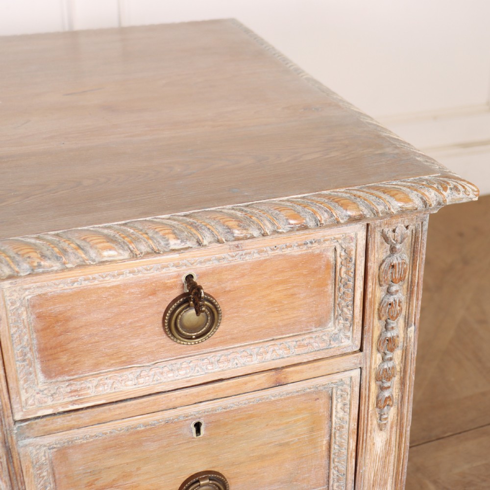 A pale bleached oak kneehole writing desk with intricate carved legs, five drawers with brass drop handles, and double X-frame stretchers. View XI