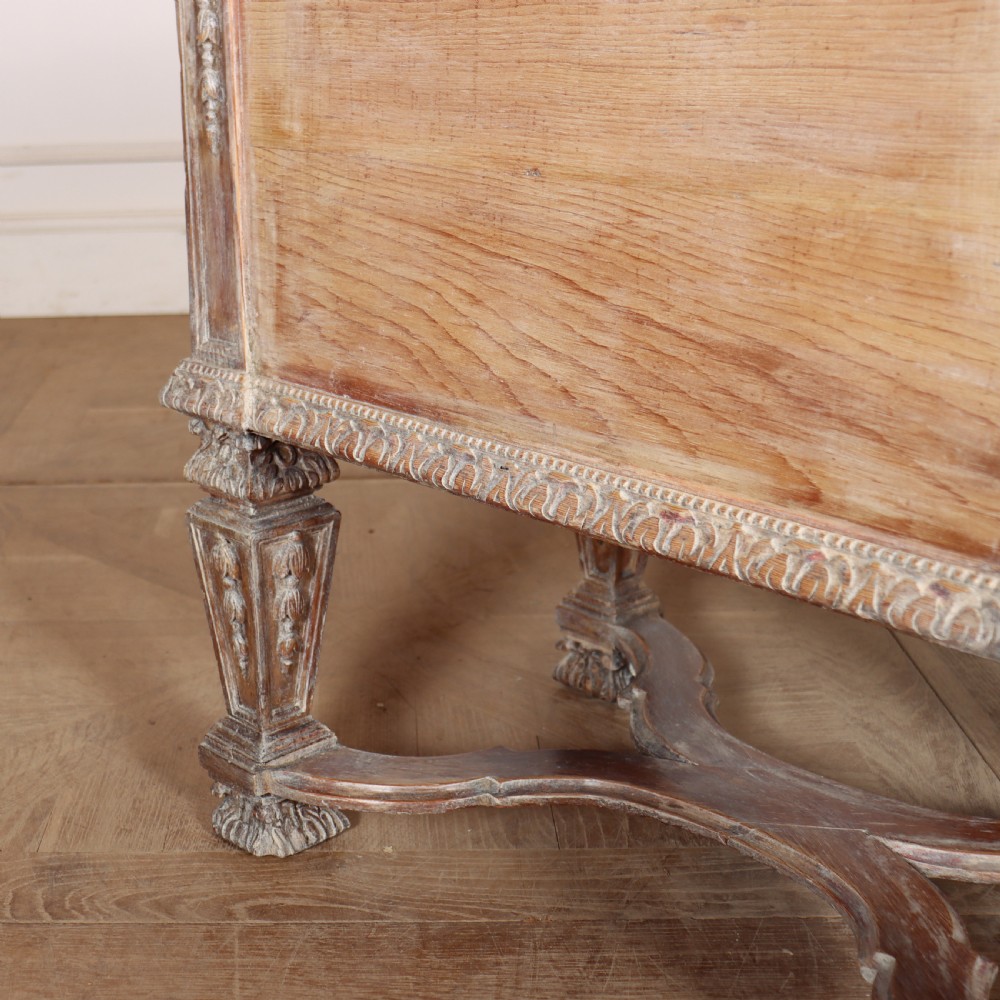 A pale bleached oak kneehole writing desk with intricate carved legs, five drawers with brass drop handles, and double X-frame stretchers. View XIII