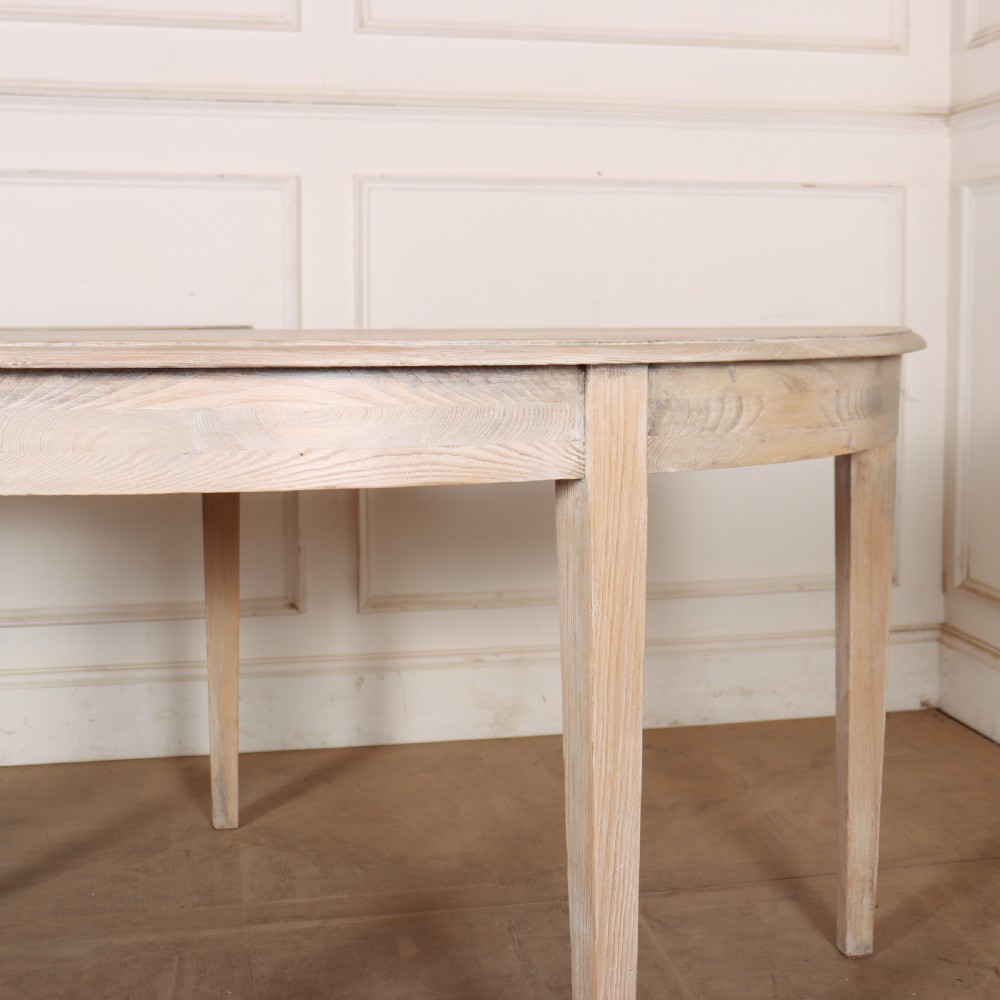 A pair of semi-circular, pale off-white painted console tables with tapered legs and flat backs designed to sit flush against a wall. View III