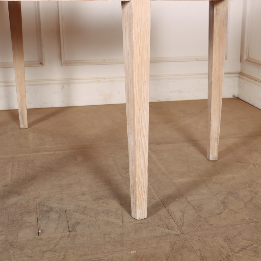 A pair of semi-circular, pale off-white painted console tables with tapered legs and flat backs designed to sit flush against a wall. View V