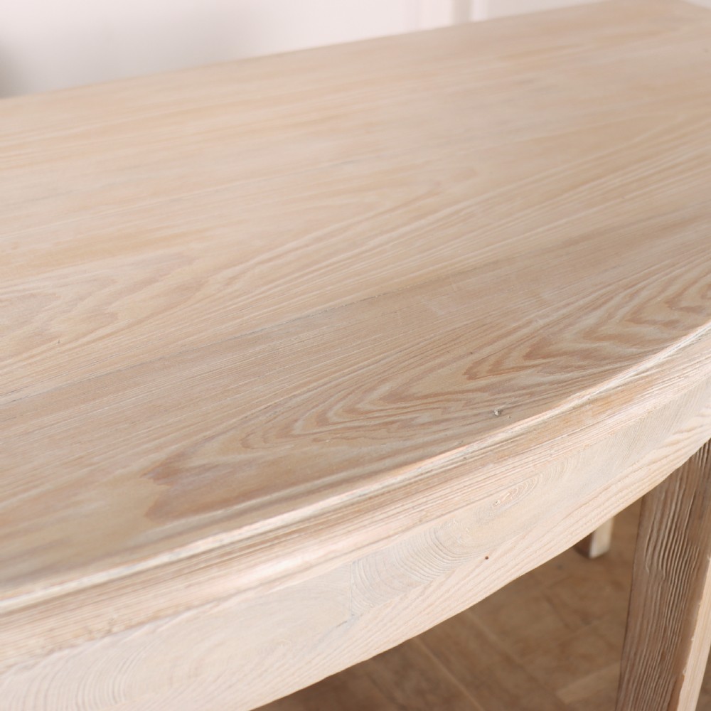 A pair of semi-circular, pale off-white painted console tables with tapered legs and flat backs designed to sit flush against a wall. View VII