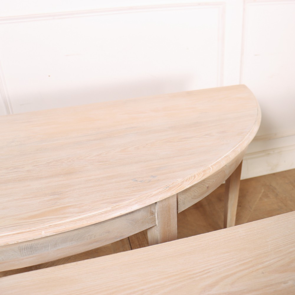 A pair of semi-circular, pale off-white painted console tables with tapered legs and flat backs designed to sit flush against a wall. View IX