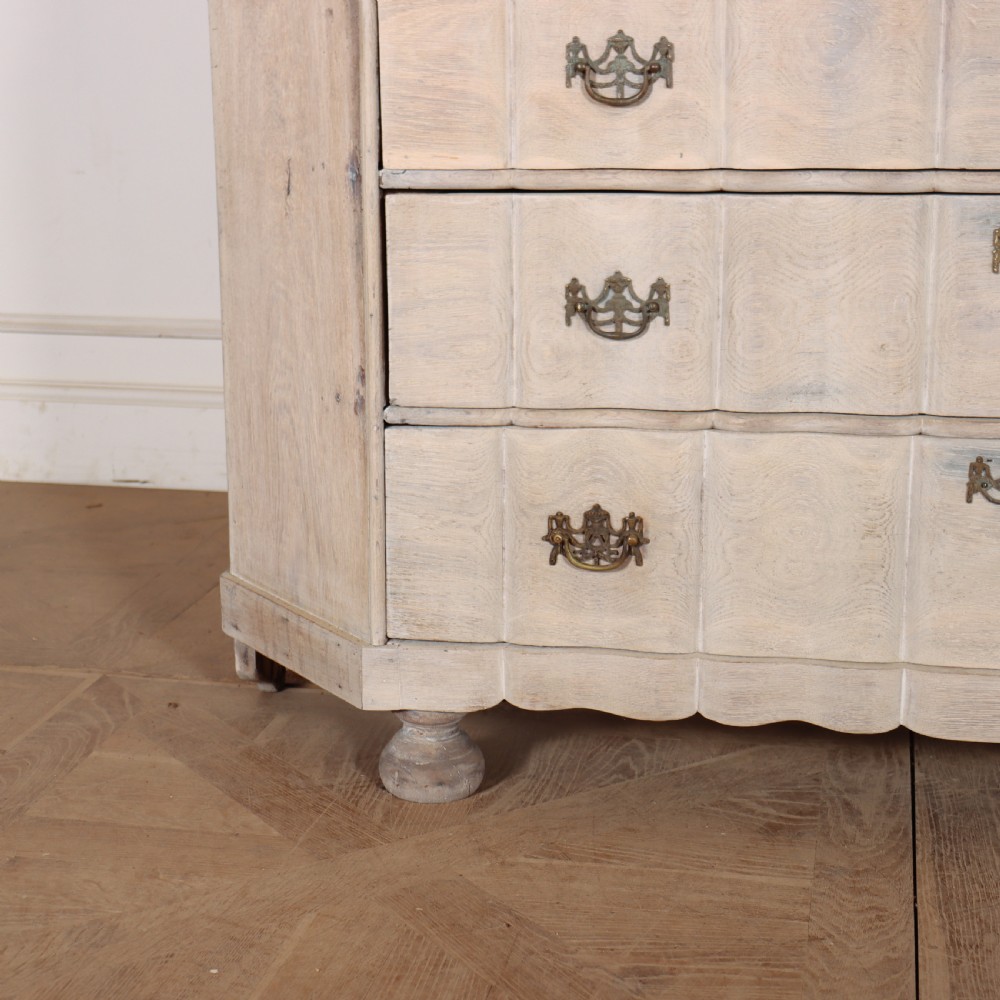 An antique Dutch glazed display cabinet with a grey-washed exterior, green painted interior, curved cresting rail, and three drawers in the base. View II