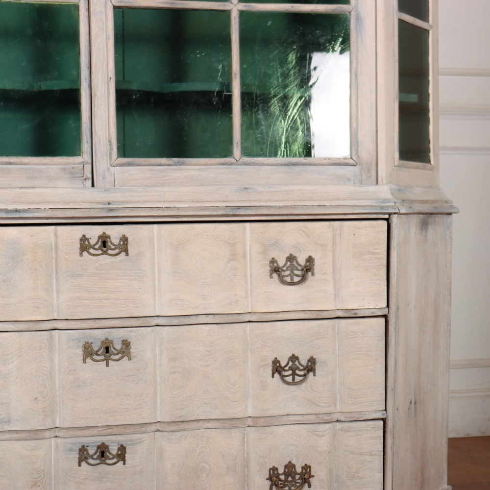 An antique Dutch glazed display cabinet with a grey-washed exterior, green painted interior, curved cresting rail, and three drawers in the base. View IV