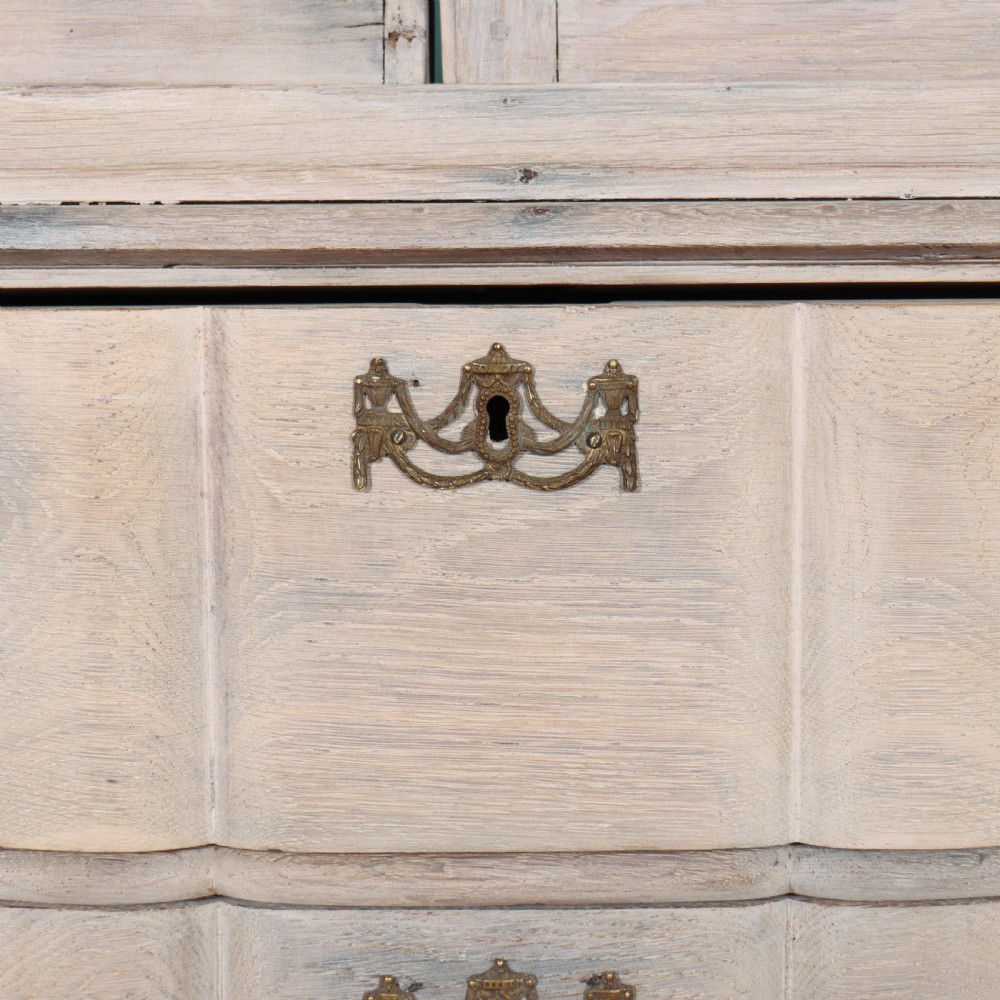 An antique Dutch glazed display cabinet with a grey-washed exterior, green painted interior, curved cresting rail, and three drawers in the base. View VI