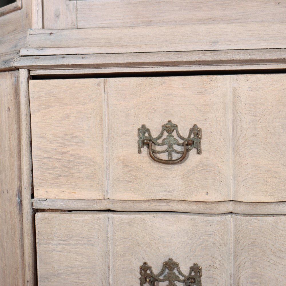 An antique Dutch glazed display cabinet with a grey-washed exterior, green painted interior, curved cresting rail, and three drawers in the base. View VII
