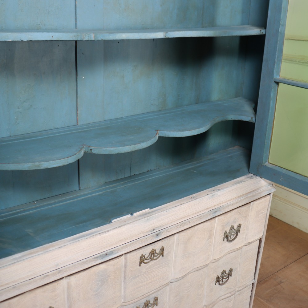 An antique Dutch glazed display cabinet with a grey-washed exterior, green painted interior, curved cresting rail, and three drawers in the base. View XII