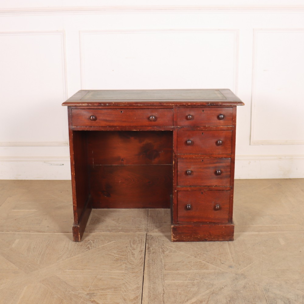 An antique mahogany childs writing desk with a green leather inset top, one wide frieze drawer, and a flight of four right-hand drawers with turned knobs.