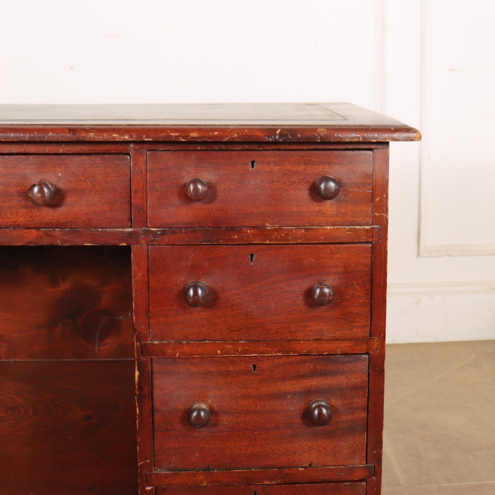 An antique mahogany childs writing desk with a green leather inset top, one wide frieze drawer, and a flight of four right-hand drawers with turned knobs. View V