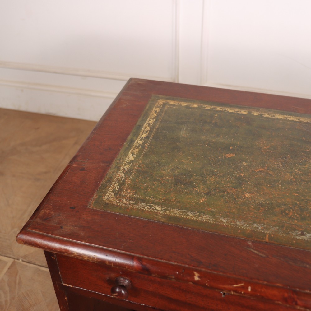 An antique mahogany childs writing desk with a green leather inset top, one wide frieze drawer, and a flight of four right-hand drawers with turned knobs. View VII