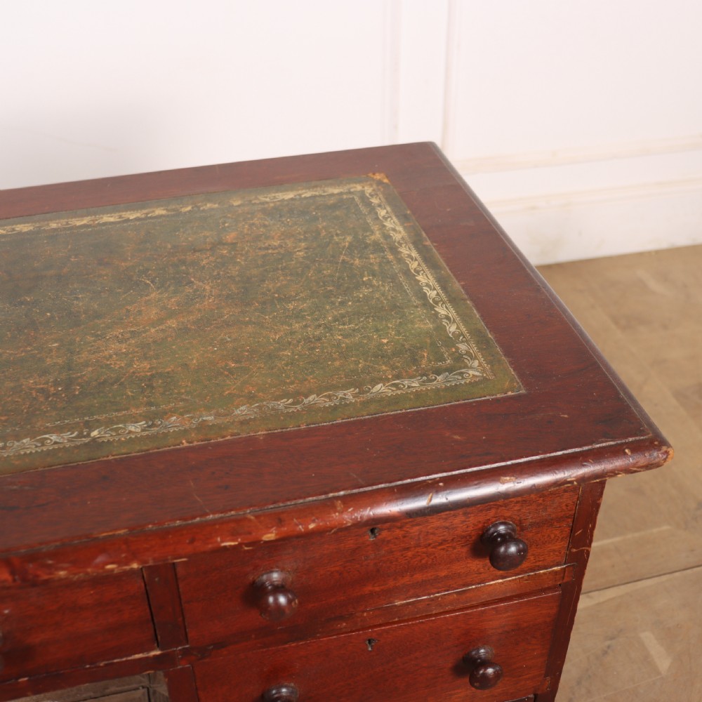 An antique mahogany childs writing desk with a green leather inset top, one wide frieze drawer, and a flight of four right-hand drawers with turned knobs. View VIII