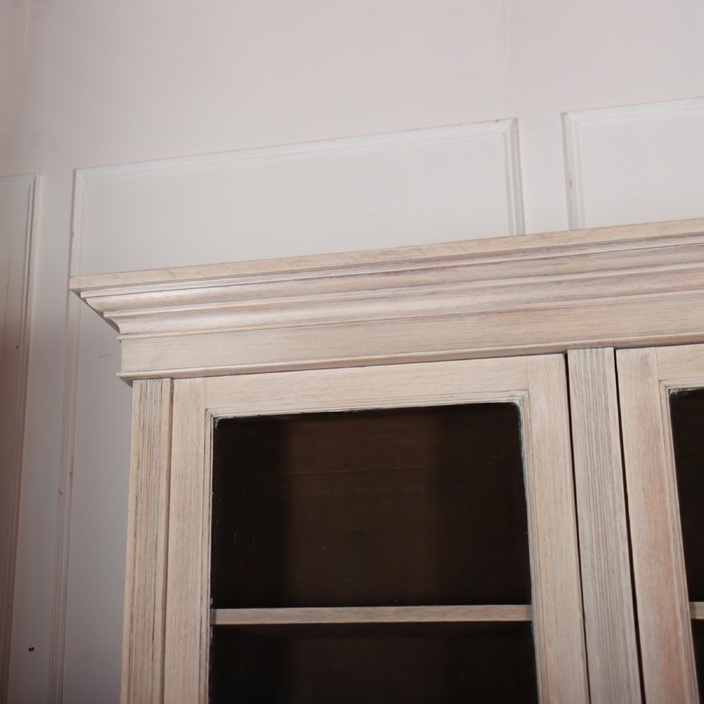 A pale English oak two-part library bookcase featuring three upper glazed doors and three lower solid panelled cupboard doors. View II
