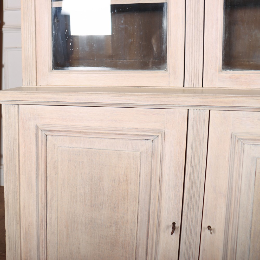 A pale English oak two-part library bookcase featuring three upper glazed doors and three lower solid panelled cupboard doors. View III