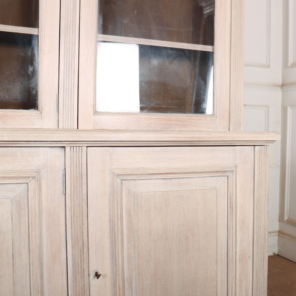 A pale English oak two-part library bookcase featuring three upper glazed doors and three lower solid panelled cupboard doors. View VI