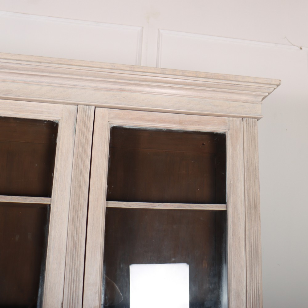 A pale English oak two-part library bookcase featuring three upper glazed doors and three lower solid panelled cupboard doors. View VII