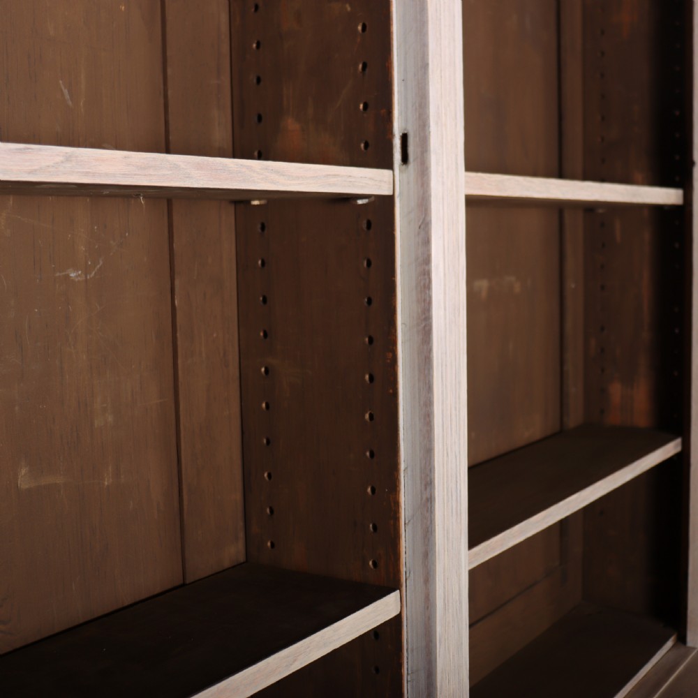 A pale English oak two-part library bookcase featuring three upper glazed doors and three lower solid panelled cupboard doors. View X