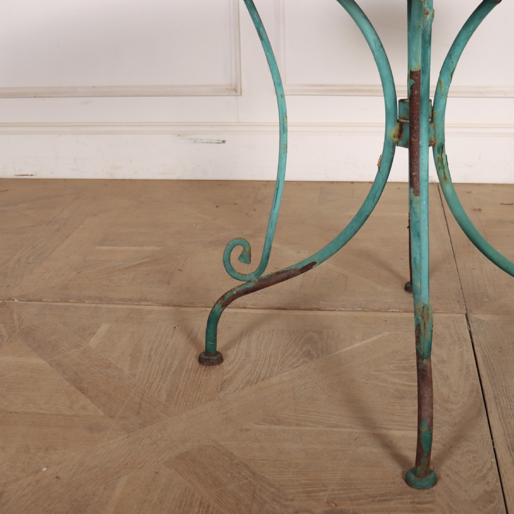 A circular garden table featuring a turquoise and off-white ceramic mosaic tile top supported by a turquoise-painted wrought iron tripod base with curved legs. View III