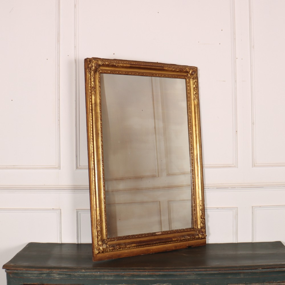 A large rectangular French antique mirror featuring a gold gilded frame with beaded moulding and carved corner details.