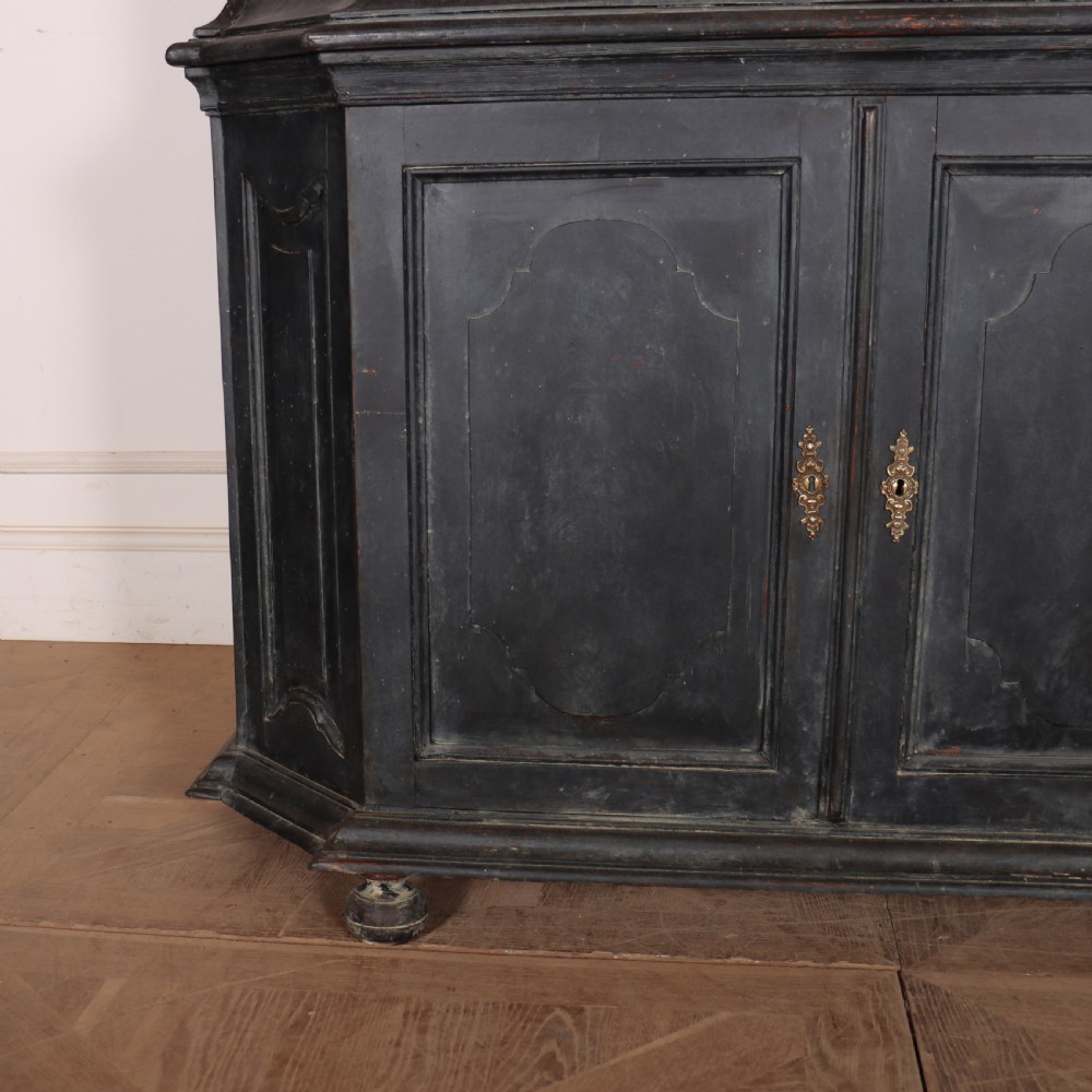 A tall, dark charcoal grey painted Dutch vitrine cabinet featuring a shaped bonnet top, glazed upper doors with curved astragal glazing bars, a cream interior, and panelled double lower doors. View V