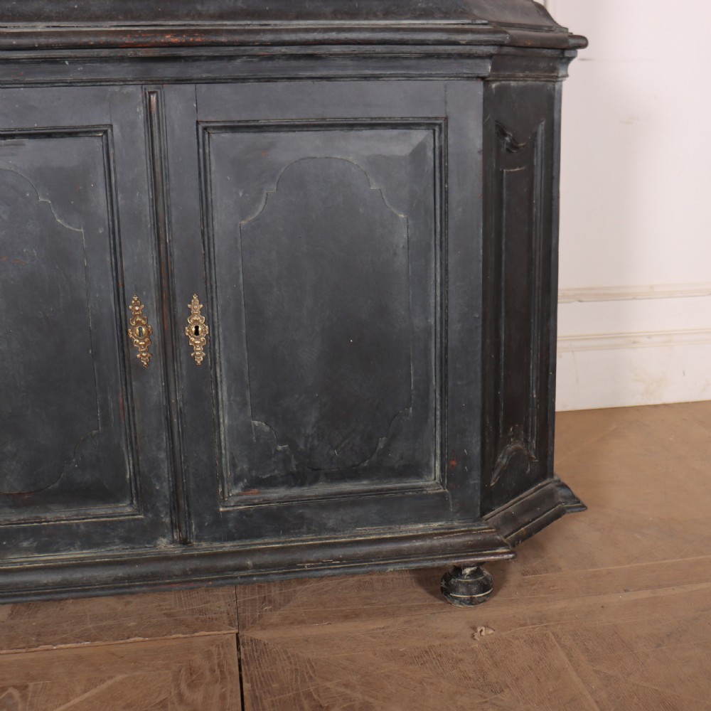 A tall, dark charcoal grey painted Dutch vitrine cabinet featuring a shaped bonnet top, glazed upper doors with curved astragal glazing bars, a cream interior, and panelled double lower doors. View VI