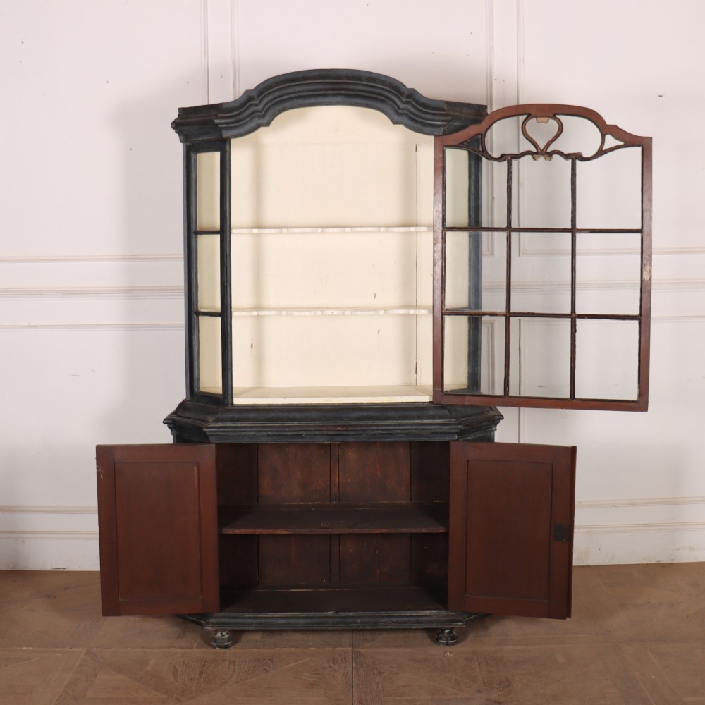 A tall, dark charcoal grey painted Dutch vitrine cabinet featuring a shaped bonnet top, glazed upper doors with curved astragal glazing bars, a cream interior, and panelled double lower doors. View VIII